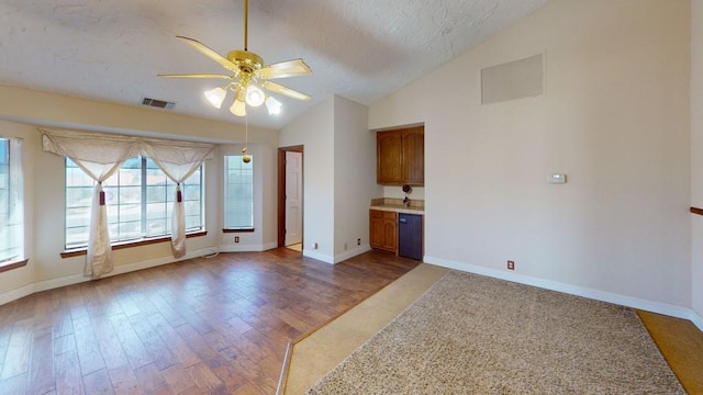 empty room with ceiling fan, lofted ceiling, wood finished floors, and visible vents