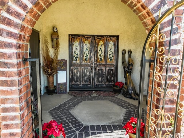 entrance to property with stucco siding, a porch, and brick siding