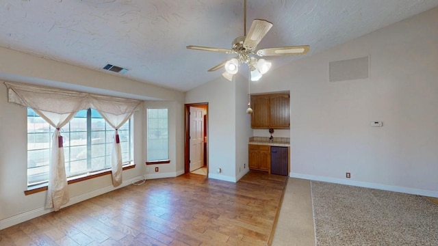unfurnished living room featuring visible vents, a ceiling fan, baseboards, and vaulted ceiling