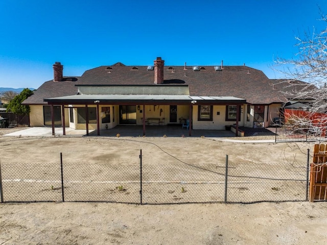 back of property featuring fence, a chimney, and a shingled roof