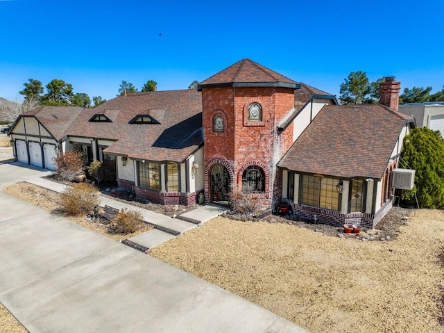 view of front of property featuring a chimney, brick siding, a shingled roof, an attached garage, and driveway