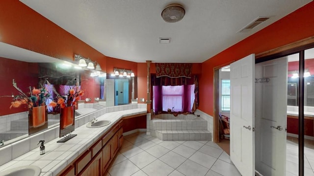 bathroom with a sink, tile patterned flooring, double vanity, visible vents, and a bath