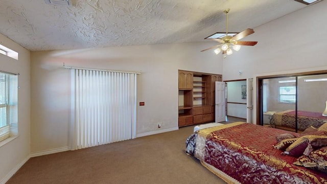 bedroom with ceiling fan, light carpet, a textured ceiling, multiple closets, and baseboards