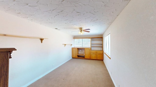 spare room with baseboards, light carpet, and a ceiling fan