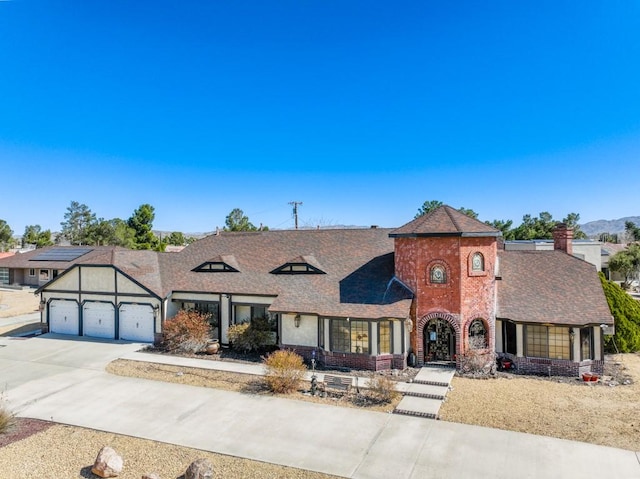 view of front facade featuring brick siding, an attached garage, driveway, and roof with shingles