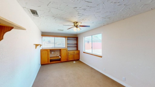 spare room featuring baseboards, a ceiling fan, light colored carpet, and visible vents