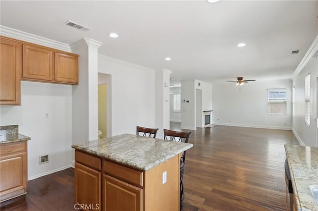 12851 Oakdale St, Eastvale, CA 92880 - kitchen featuring ornamental molding, a breakfast bar area, a ceiling fan, dark wood-type flooring, and light stone countertops