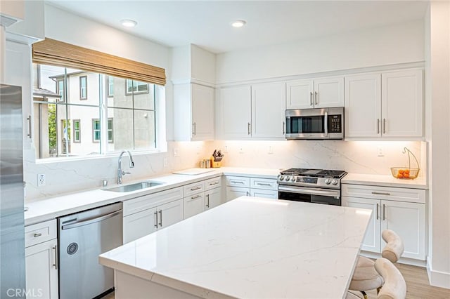 11751 Florence Ave, Santa Fe Springs, CA 90670 - kitchen with a center island, a sink, light stone counters, white cabinets, and stainless steel appliances