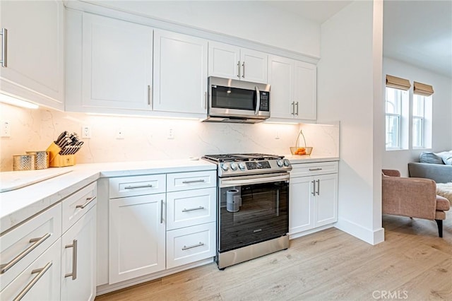 11751 Florence Ave, Santa Fe Springs, CA 90670 - kitchen with decorative backsplash, light countertops, white cabinets, light wood-style flooring, and stainless steel appliances