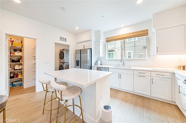 11751 Florence Ave, Santa Fe Springs, CA 90670 - kitchen with a breakfast bar, appliances with stainless steel finishes, a sink, stacked washer and clothes dryer, and white cabinetry