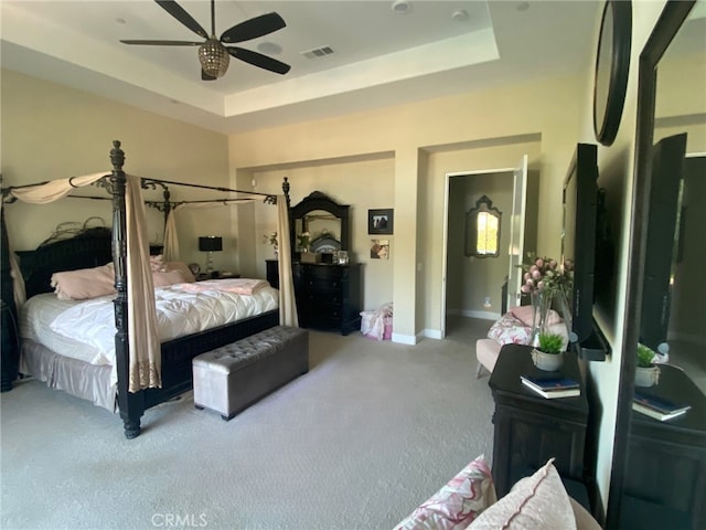 bedroom with carpet floors, a tray ceiling, visible vents, and baseboards