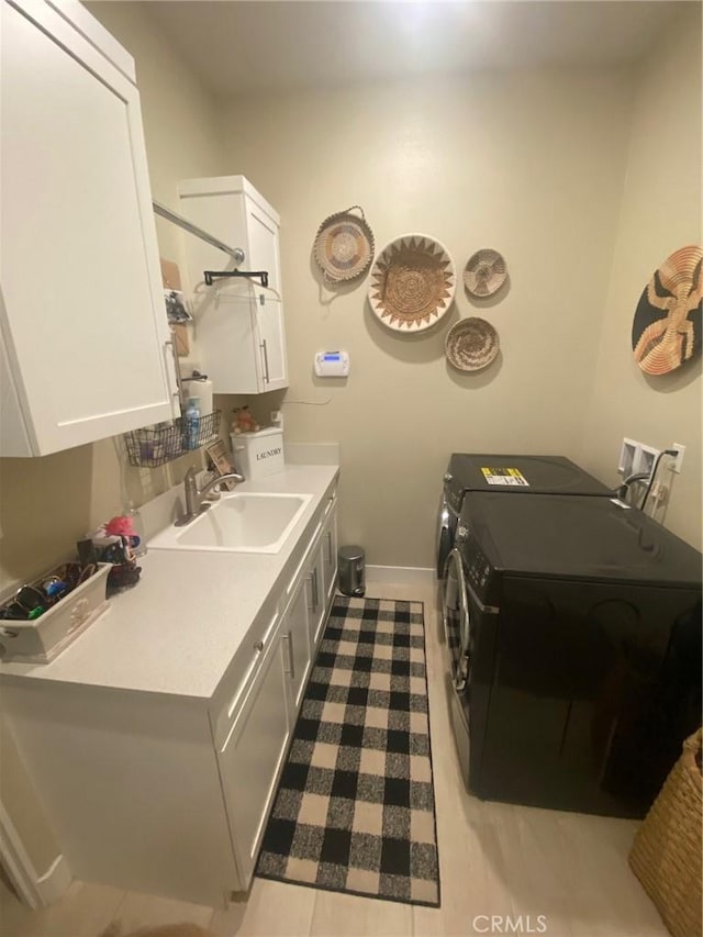 washroom with separate washer and dryer, a sink, cabinet space, and baseboards