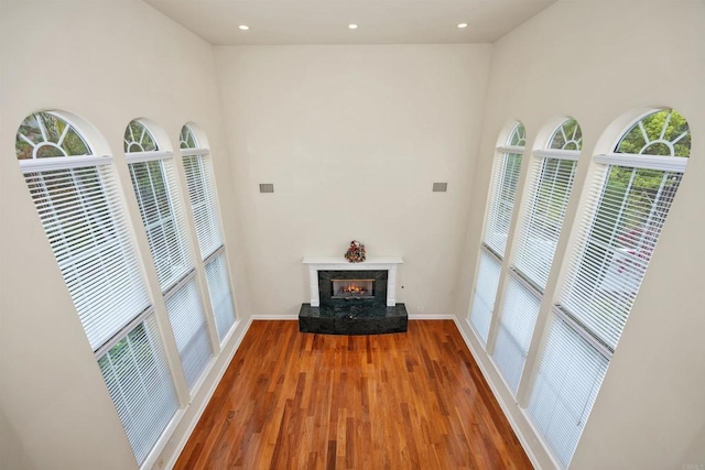 unfurnished living room featuring baseboards, recessed lighting, wood finished floors, and a premium fireplace