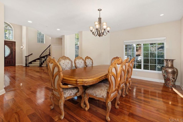 dining room featuring plenty of natural light, wood-type flooring, stairs, and a notable chandelier