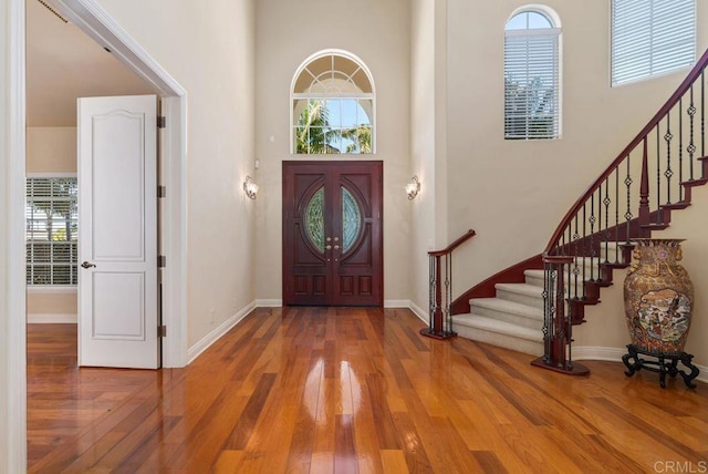 foyer entrance with stairs, plenty of natural light, hardwood / wood-style floors, and a towering ceiling