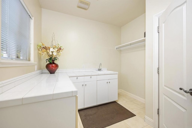 washroom featuring a sink, light tile patterned floors, and baseboards