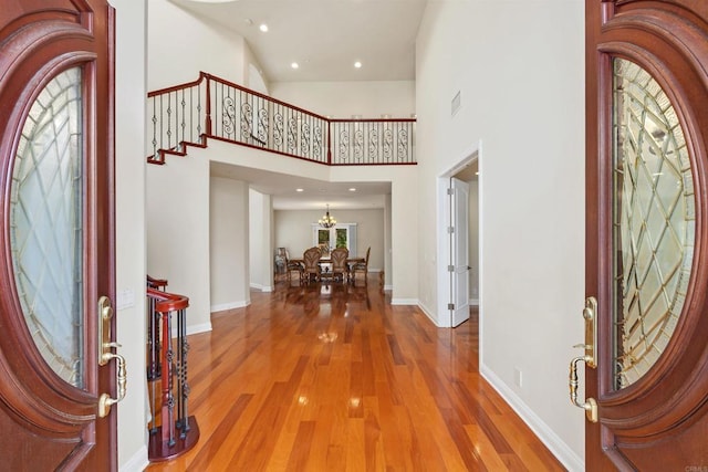 entrance foyer featuring visible vents, wood finished floors, baseboards, stairway, and a chandelier