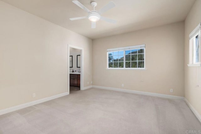 spare room with baseboards, ceiling fan, and light carpet