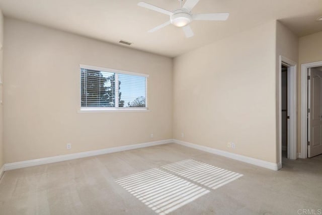 carpeted spare room featuring visible vents, a ceiling fan, and baseboards