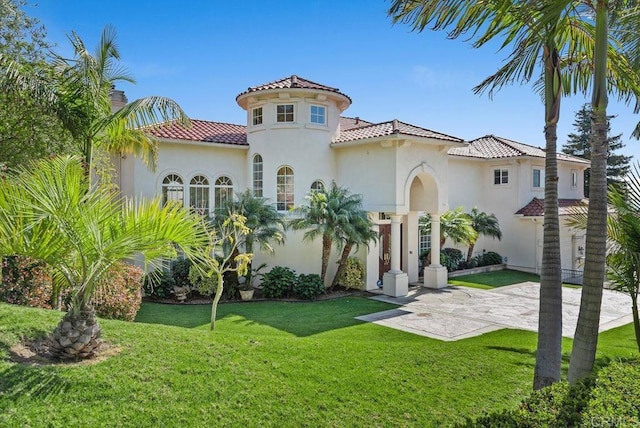 view of front facade featuring a tiled roof, a chimney, stucco siding, and a front lawn