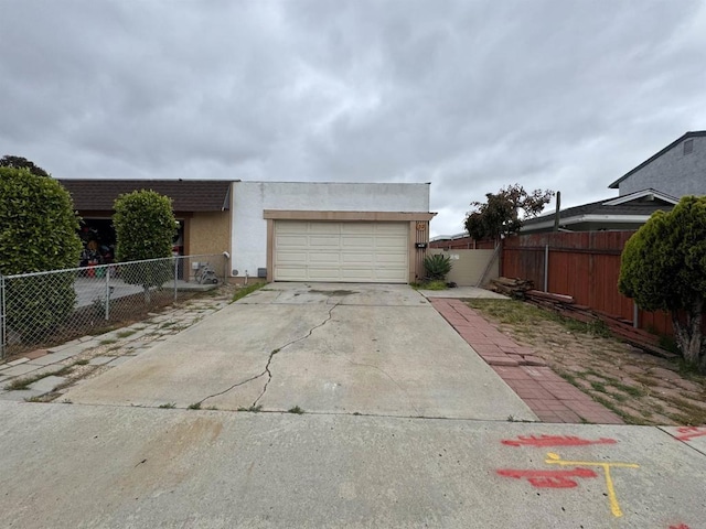 view of side of property with concrete driveway, stucco siding, fence, and a garage