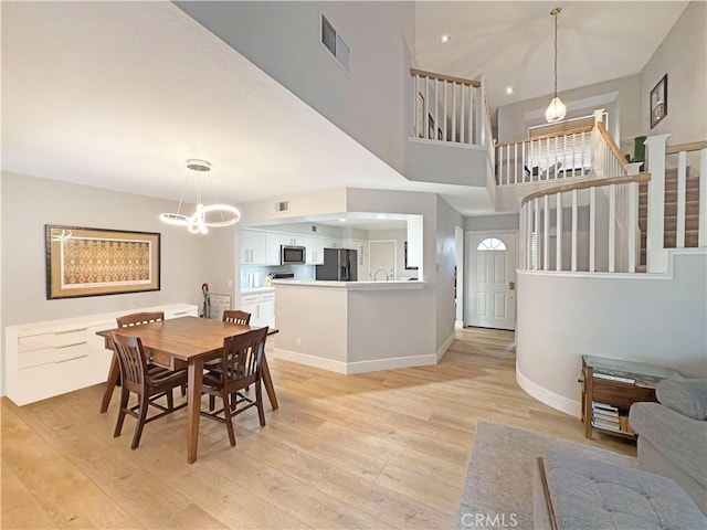 dining room featuring visible vents, baseboards, stairway, light wood finished floors, and a notable chandelier