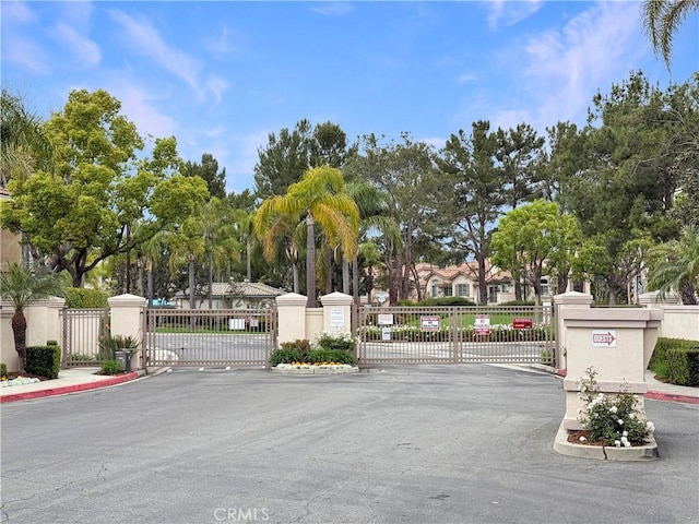 view of street with a gate, a gated entry, curbs, and sidewalks