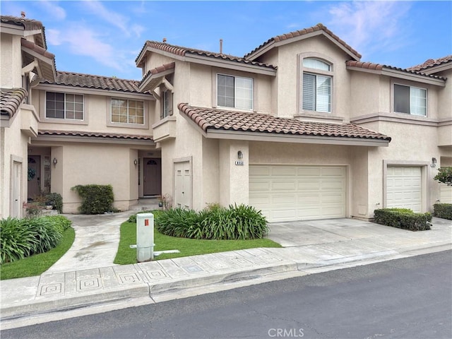 view of property with an attached garage, concrete driveway, a tile roof, and stucco siding