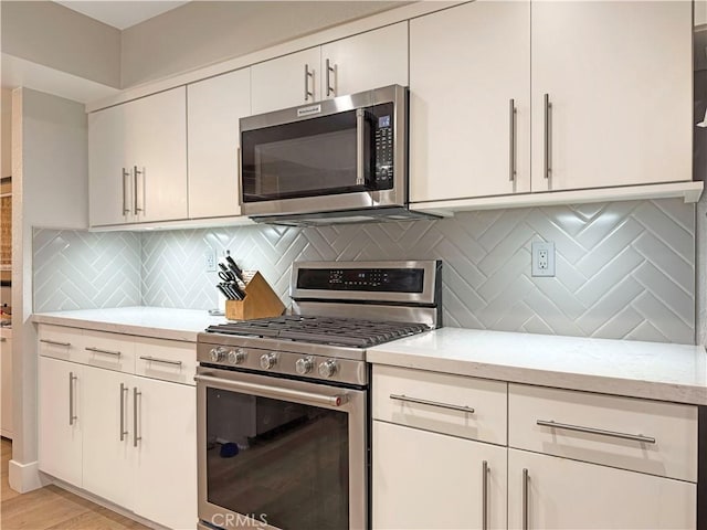 kitchen featuring light wood-style floors, decorative backsplash, appliances with stainless steel finishes, and light stone countertops