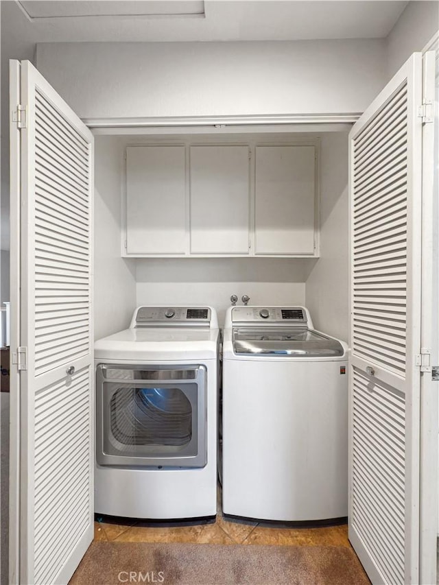 clothes washing area featuring separate washer and dryer and cabinet space