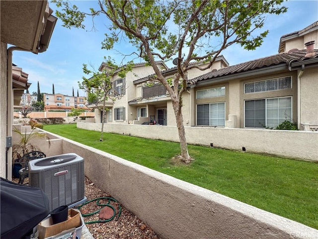 view of side of property with central air condition unit, stucco siding, a lawn, and a tiled roof