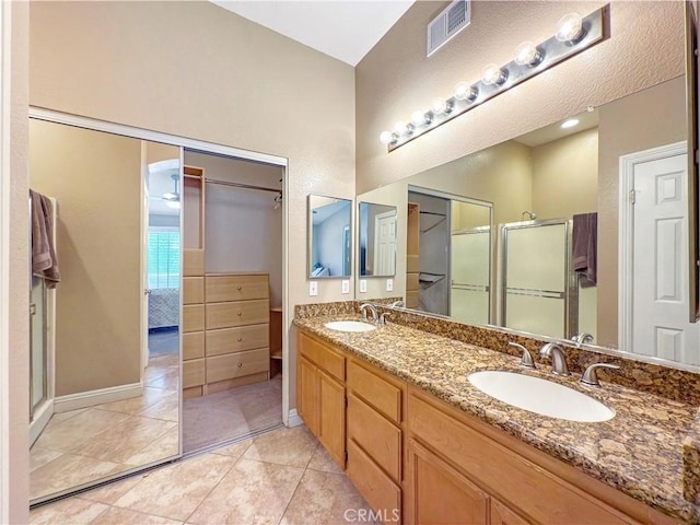 ensuite bathroom with visible vents, a sink, a stall shower, and double vanity