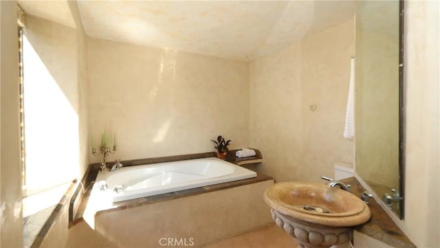 bathroom featuring toilet, tile patterned floors, and a bath