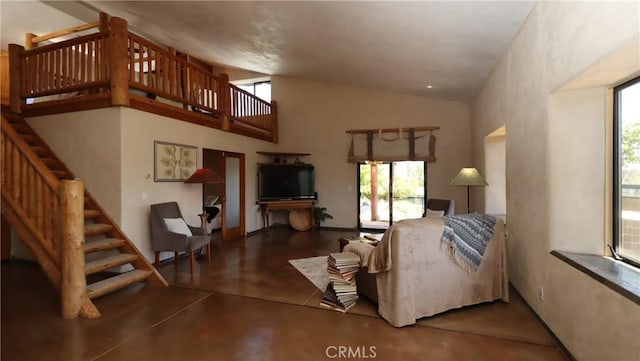 living area with concrete flooring, a wealth of natural light, stairway, and high vaulted ceiling