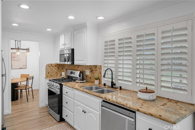 kitchen featuring a sink, appliances with stainless steel finishes, white cabinets, and crown molding