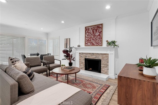 living room with recessed lighting, ornamental molding, light wood finished floors, and a fireplace