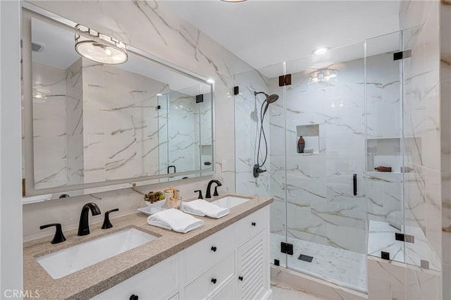 bathroom with a sink, a marble finish shower, and double vanity