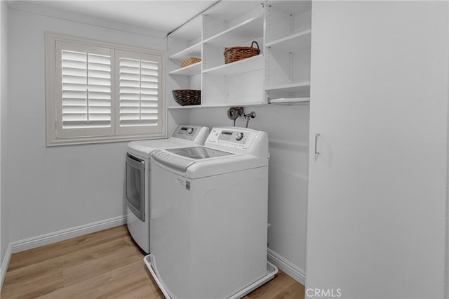 laundry area featuring baseboards, laundry area, light wood-type flooring, and washing machine and clothes dryer