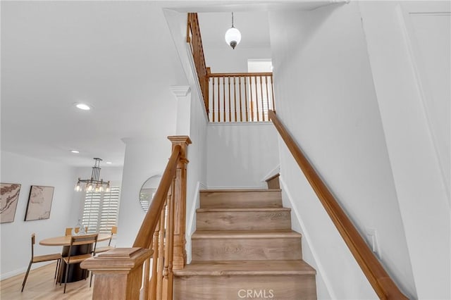 staircase with baseboards, recessed lighting, wood finished floors, and a notable chandelier