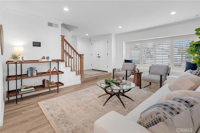 living room with crown molding, light wood-style floors, recessed lighting, baseboards, and stairway