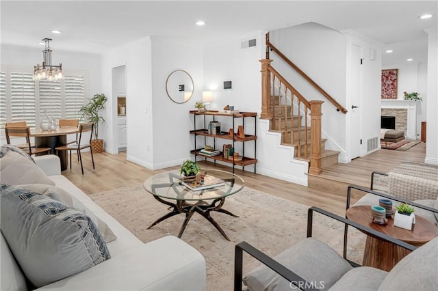 living area with an inviting chandelier, light wood-style flooring, stairs, recessed lighting, and visible vents
