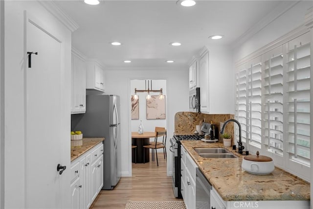 kitchen with light wood-style floors, recessed lighting, white cabinets, a sink, and appliances with stainless steel finishes