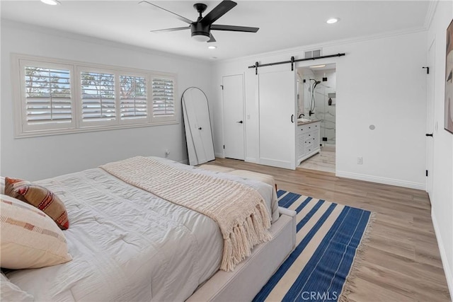 bedroom featuring visible vents, a barn door, ornamental molding, and light wood-type flooring