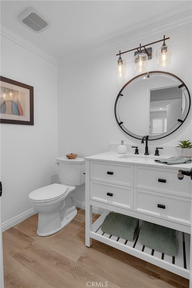 bathroom with visible vents, baseboards, wood finished floors, and toilet