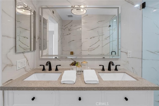 bathroom with double vanity, tile walls, a sink, and visible vents