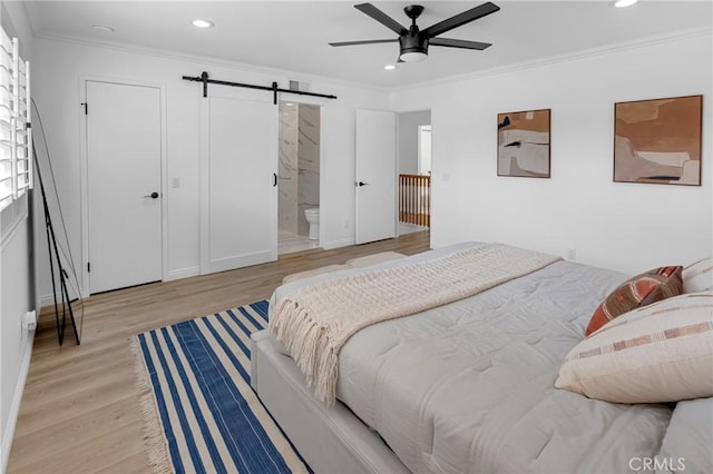 bedroom with recessed lighting, a barn door, wood finished floors, and ornamental molding