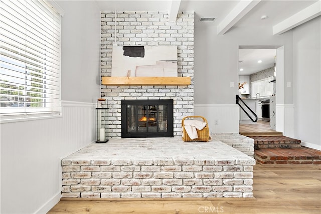 12748 Paramount Blvd, Downey, CA 90242 - living room featuring wood finished floors, a brick fireplace, beam ceiling, and a wainscoted wall