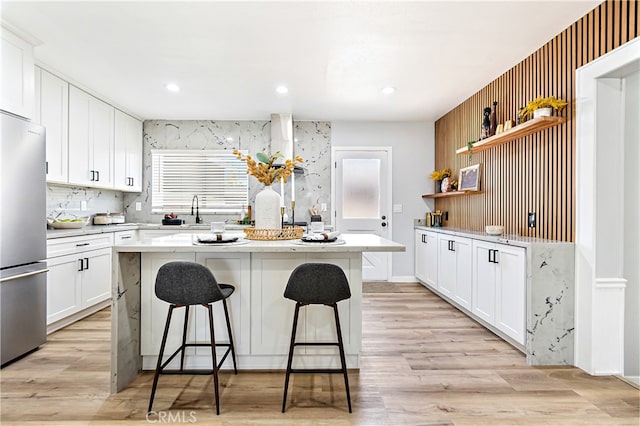 12748 Paramount Blvd, Downey, CA 90242 - kitchen with open shelves, freestanding refrigerator, a kitchen breakfast bar, a center island, and white cabinets