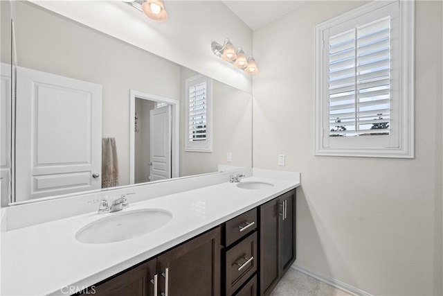 full bathroom featuring double vanity, baseboards, and a sink