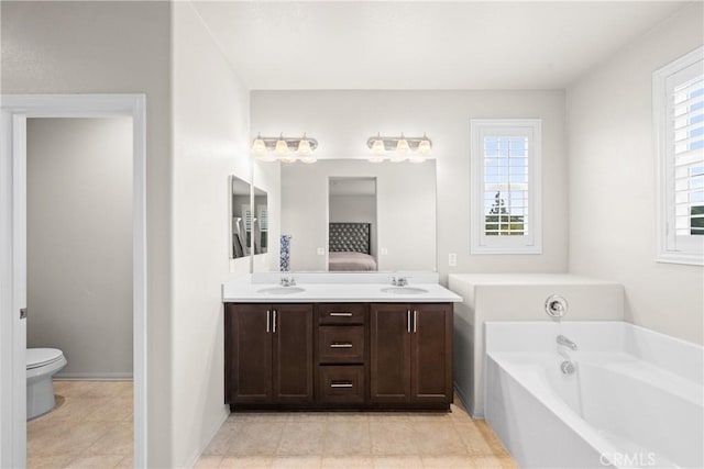 ensuite bathroom featuring double vanity, a sink, a bath, and toilet